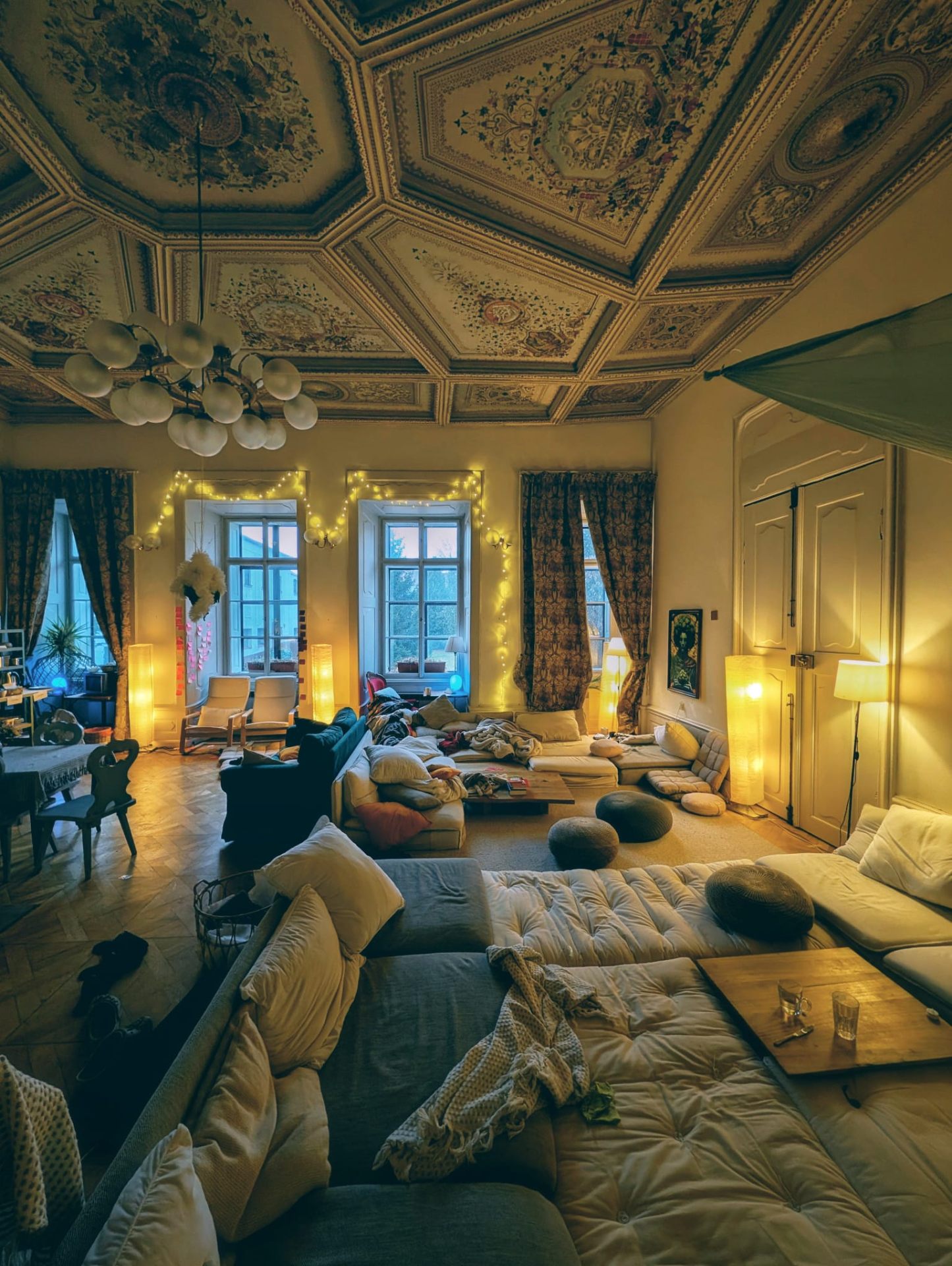 A common room filled with cushions and lamplight